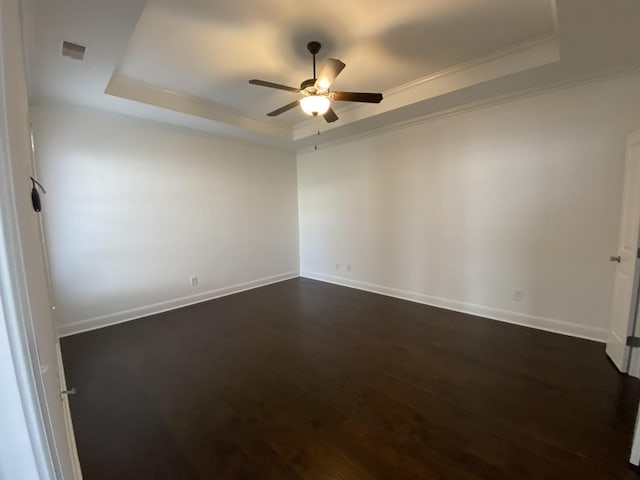 empty room featuring a tray ceiling, ceiling fan, dark hardwood / wood-style floors, and ornamental molding