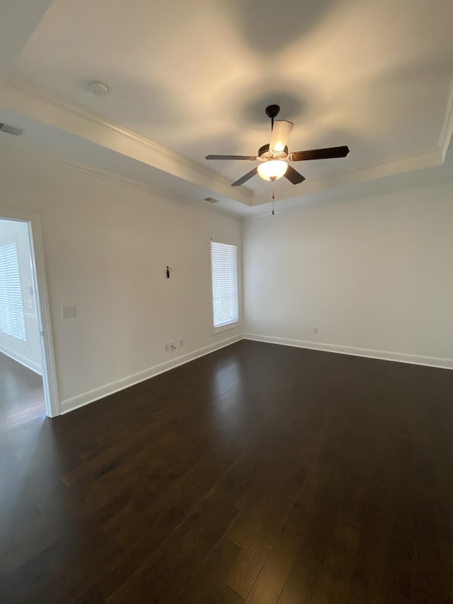 empty room with a tray ceiling, crown molding, ceiling fan, and dark hardwood / wood-style floors