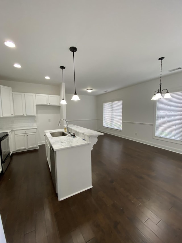 kitchen with white cabinets, hanging light fixtures, dark wood-type flooring, and an island with sink