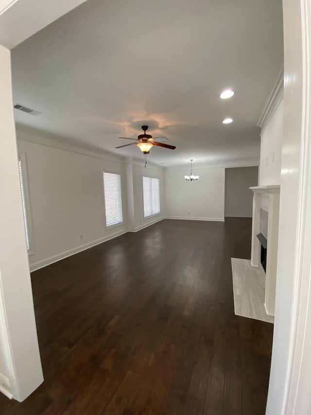 unfurnished living room with ceiling fan with notable chandelier, dark hardwood / wood-style flooring, and crown molding