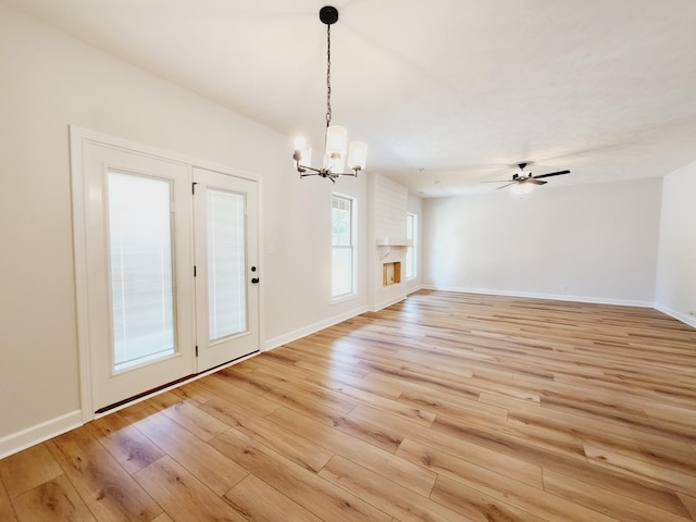 interior space with ceiling fan with notable chandelier and light hardwood / wood-style flooring