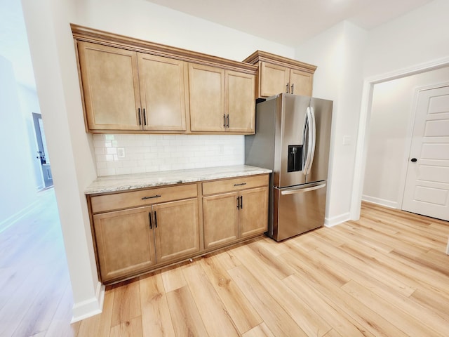 kitchen with light stone countertops, stainless steel refrigerator with ice dispenser, light wood-type flooring, and decorative backsplash