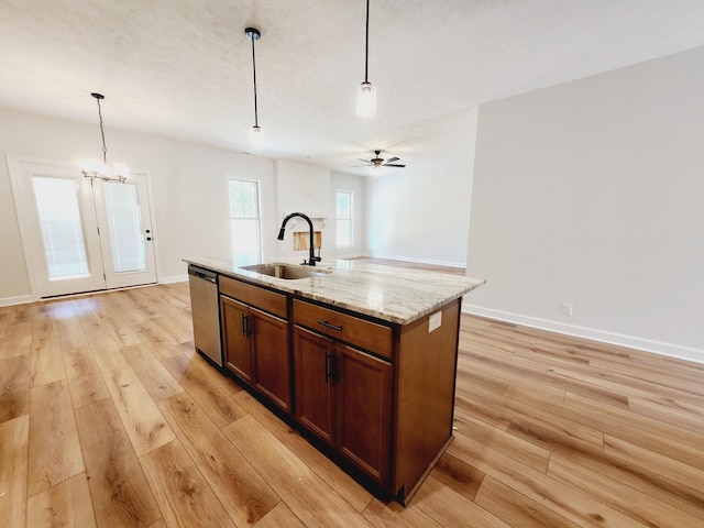 kitchen with sink, hanging light fixtures, light hardwood / wood-style flooring, stainless steel dishwasher, and a kitchen island with sink