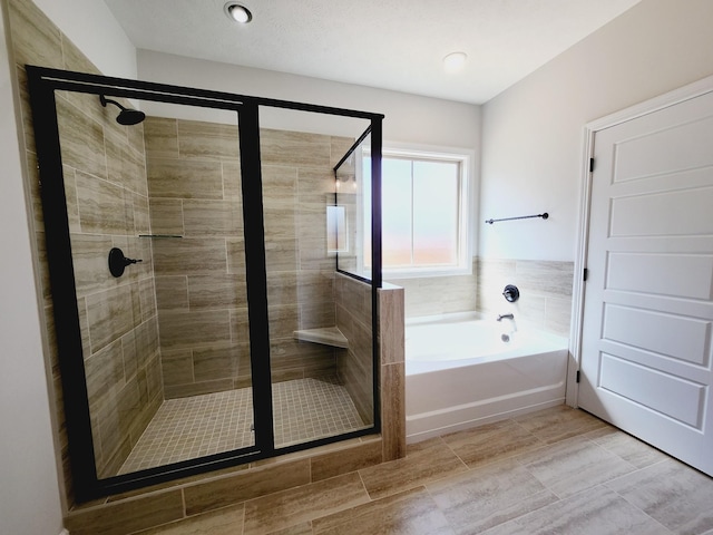 bathroom with a textured ceiling and shower with separate bathtub