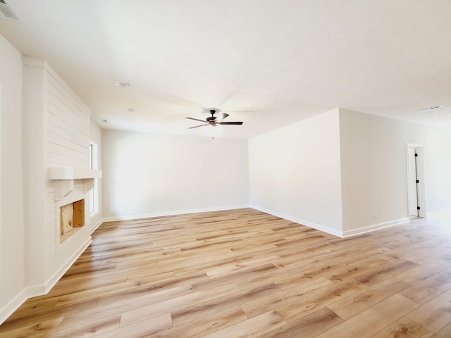 unfurnished living room with ceiling fan, a large fireplace, and light hardwood / wood-style floors