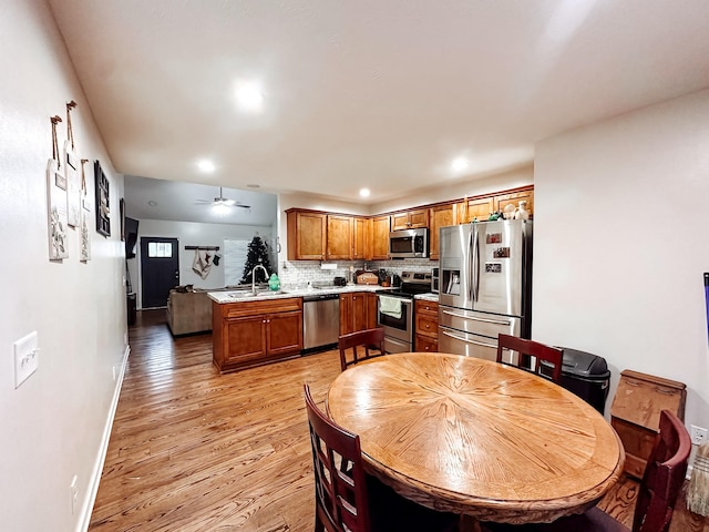 kitchen with kitchen peninsula, backsplash, stainless steel appliances, sink, and light hardwood / wood-style floors