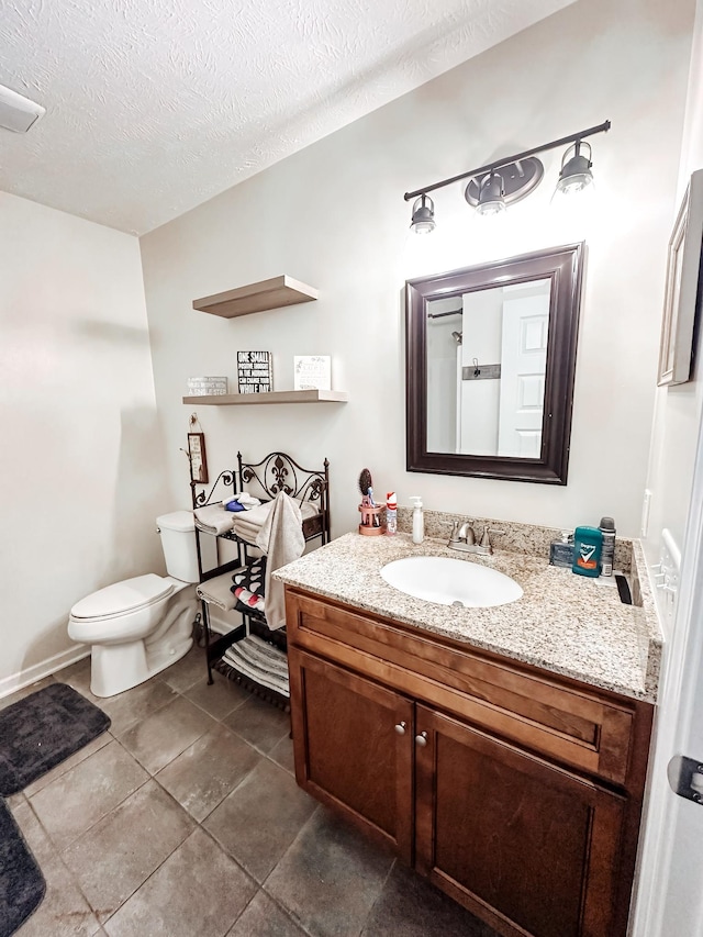 bathroom featuring tile patterned flooring, vanity, toilet, and a textured ceiling