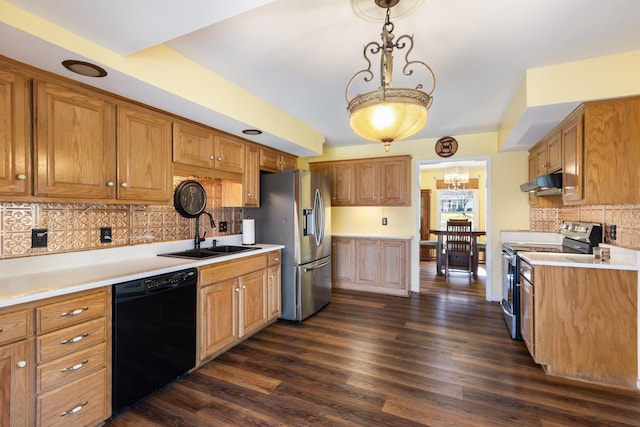 kitchen with appliances with stainless steel finishes, tasteful backsplash, dark wood-type flooring, sink, and hanging light fixtures