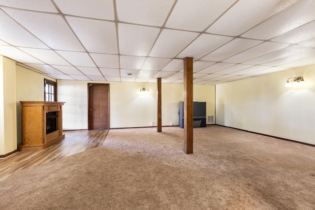 basement with a paneled ceiling and light hardwood / wood-style floors