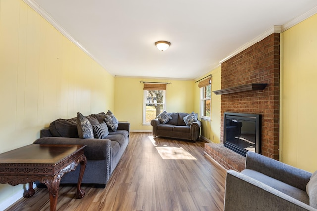 living room featuring a brick fireplace, wood-type flooring, and ornamental molding