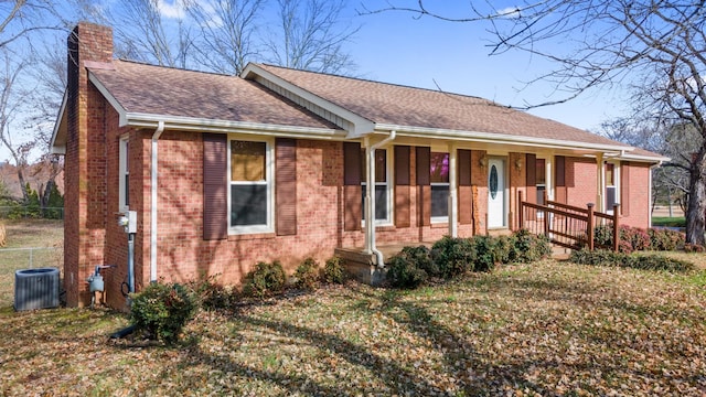 single story home with covered porch, central AC unit, and a front yard