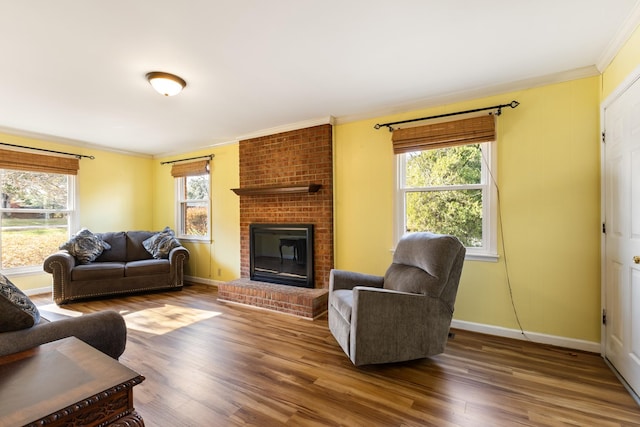 living room with a brick fireplace, plenty of natural light, ornamental molding, and hardwood / wood-style flooring