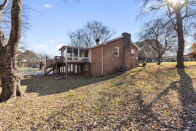 back of property with central air condition unit, a sunroom, a lawn, and a deck