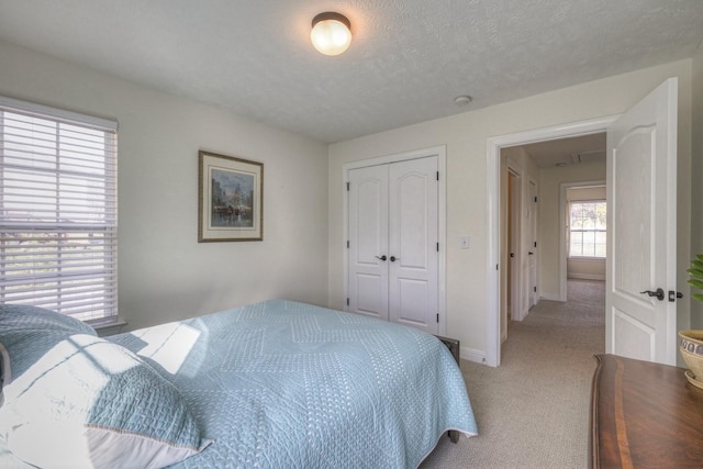 bedroom with light carpet, a textured ceiling, and a closet