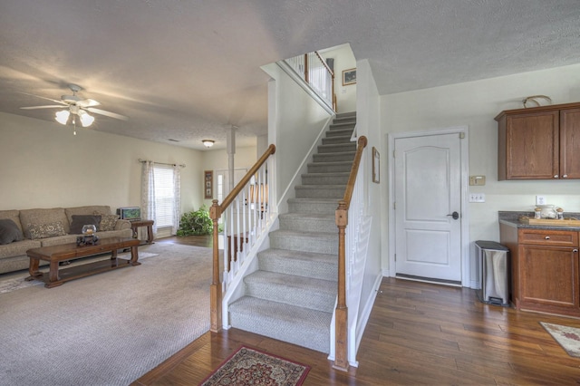 staircase featuring ceiling fan, wood-type flooring, and a textured ceiling