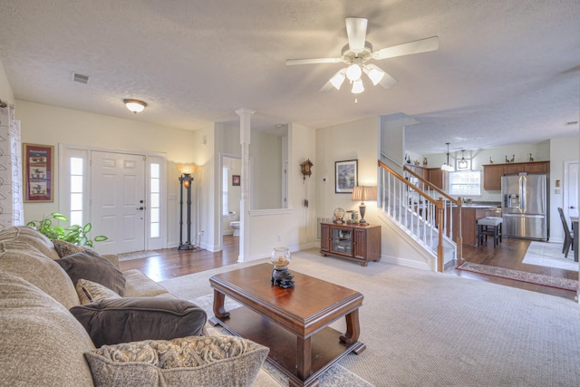 living room featuring ceiling fan, light wood-type flooring, and a textured ceiling