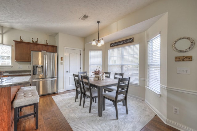 dining space featuring a textured ceiling, a wealth of natural light, and dark wood-type flooring