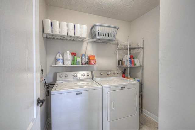 clothes washing area with washer and clothes dryer, light hardwood / wood-style floors, and a textured ceiling