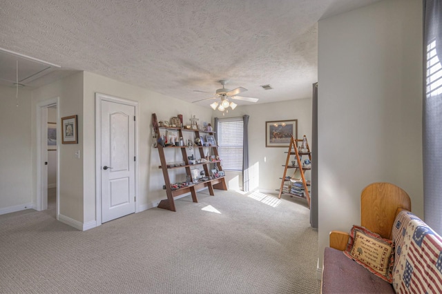 sitting room featuring ceiling fan, carpet floors, and a textured ceiling