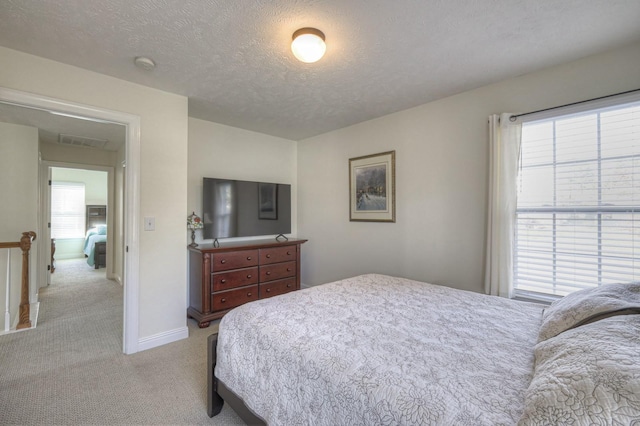 bedroom featuring light colored carpet and a textured ceiling