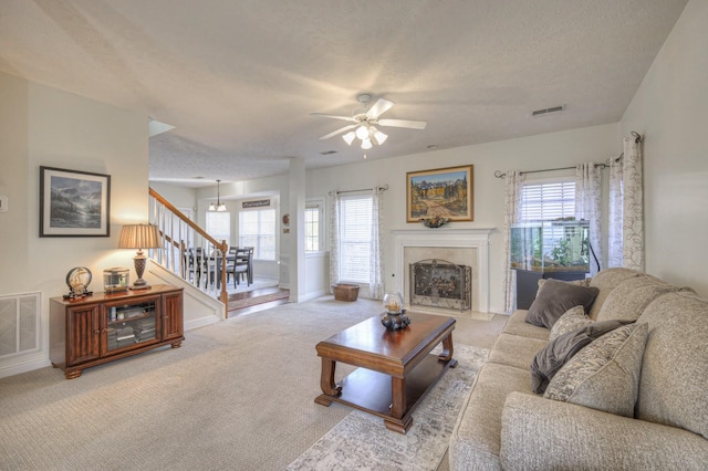 carpeted living room with ceiling fan and a textured ceiling