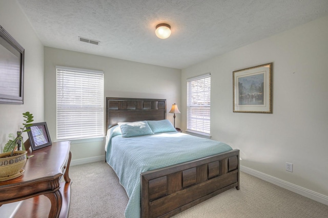 bedroom with light colored carpet and a textured ceiling