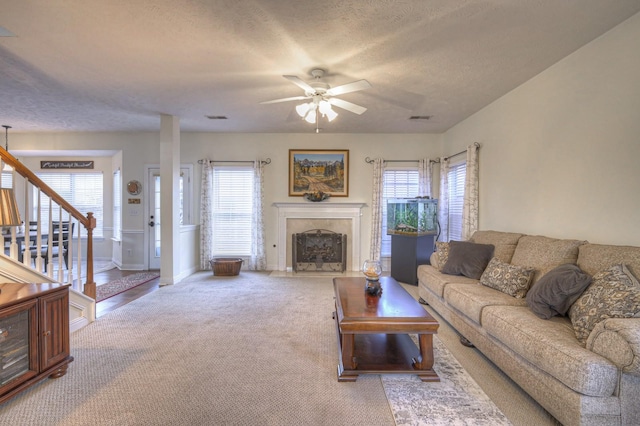 living room with a textured ceiling, carpet floors, ceiling fan, and a healthy amount of sunlight