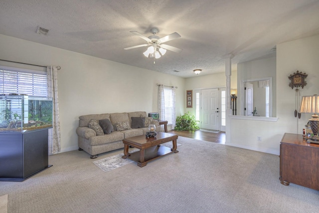 carpeted living room featuring ceiling fan and a textured ceiling