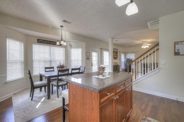 kitchen with dark hardwood / wood-style floors, a center island, hanging light fixtures, and a wealth of natural light