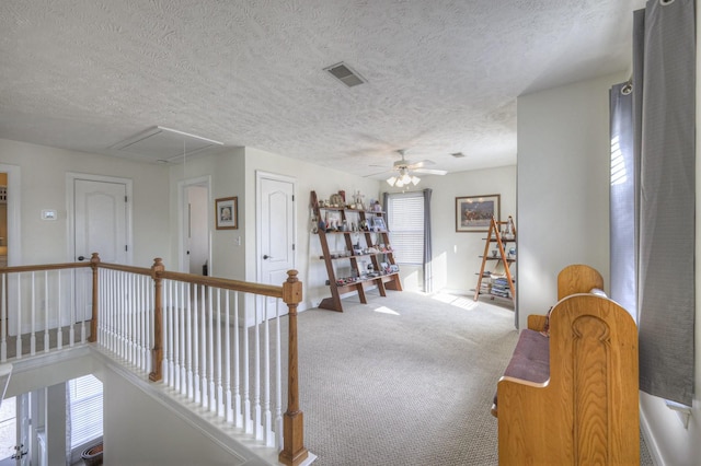 hall with a textured ceiling, carpet floors, and a healthy amount of sunlight