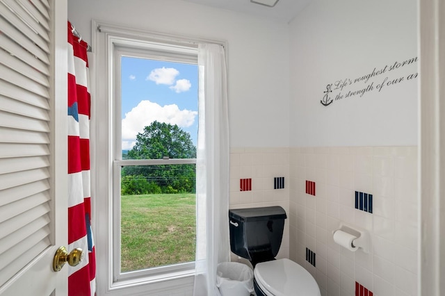 bathroom featuring plenty of natural light, toilet, and tile walls