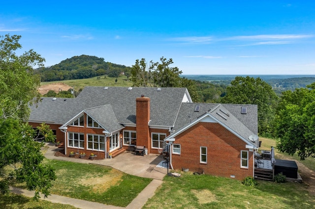 back of house featuring a sunroom, a yard, a patio, and a wooden deck