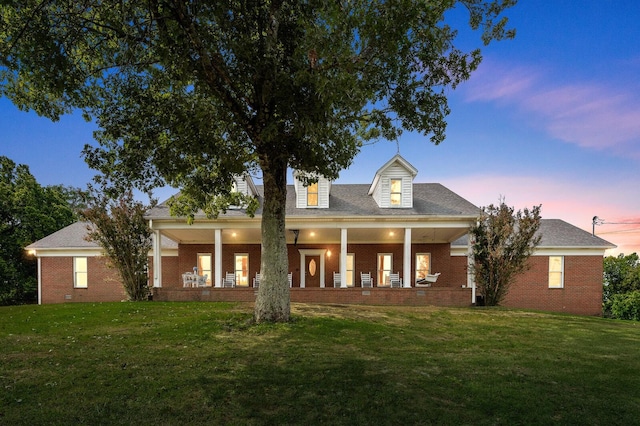 view of front of home featuring covered porch and a lawn