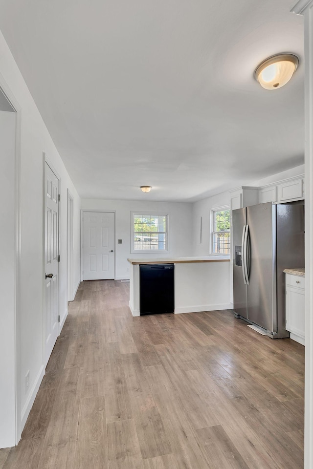 kitchen featuring black dishwasher, wood finished floors, stainless steel fridge, and white cabinets