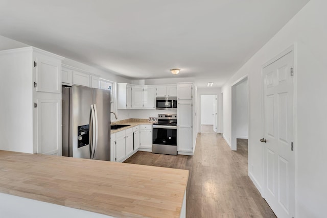 kitchen with white cabinets, stainless steel appliances, and wood finished floors