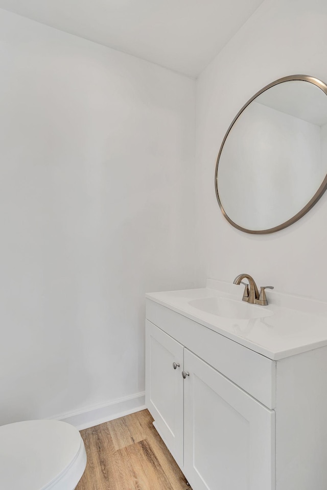 bathroom with baseboards, vanity, toilet, and wood finished floors