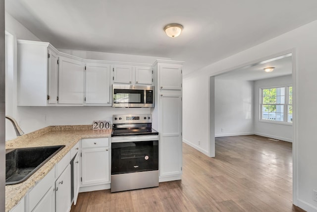 kitchen featuring light wood-type flooring, white cabinetry, appliances with stainless steel finishes, and a sink