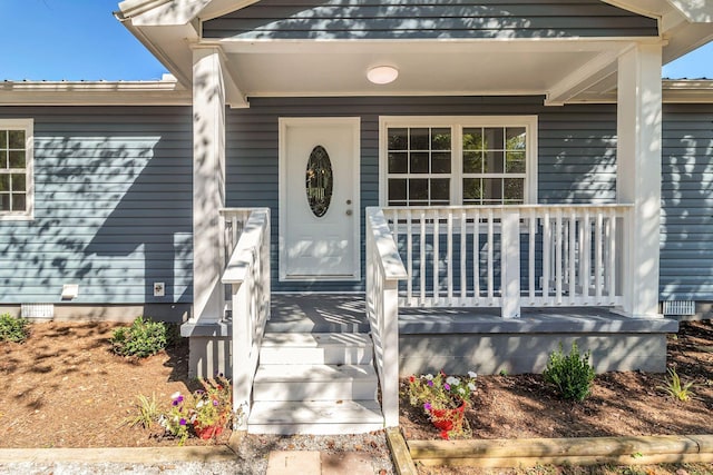 view of exterior entry featuring covered porch and crawl space