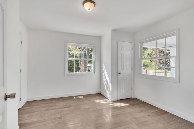 interior space featuring light wood finished floors, plenty of natural light, visible vents, and baseboards