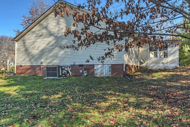 view of side of home with central AC unit and a lawn