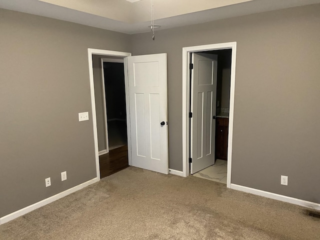 unfurnished bedroom featuring connected bathroom and light carpet