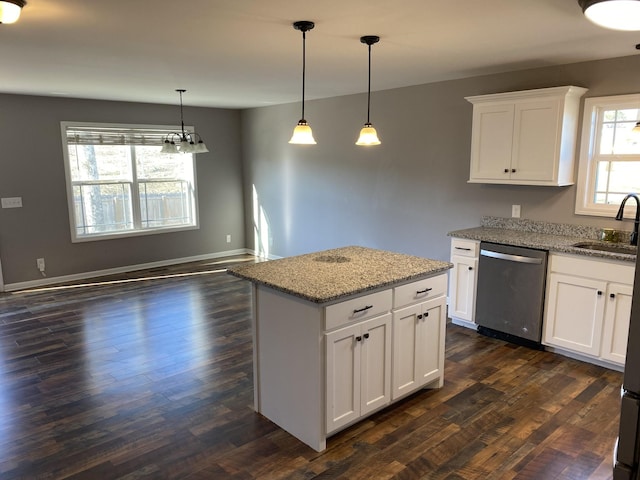 kitchen featuring pendant lighting, sink, white cabinetry, light stone counters, and stainless steel dishwasher