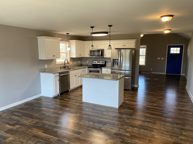 kitchen featuring sink, stainless steel appliances, white cabinets, a kitchen island, and decorative light fixtures