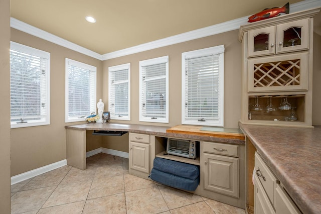 office area featuring built in desk, crown molding, and light tile patterned flooring