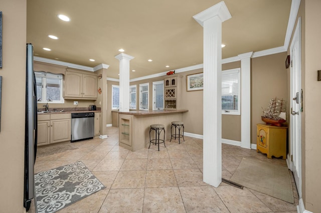 kitchen with dishwasher, crown molding, a breakfast bar area, and decorative columns