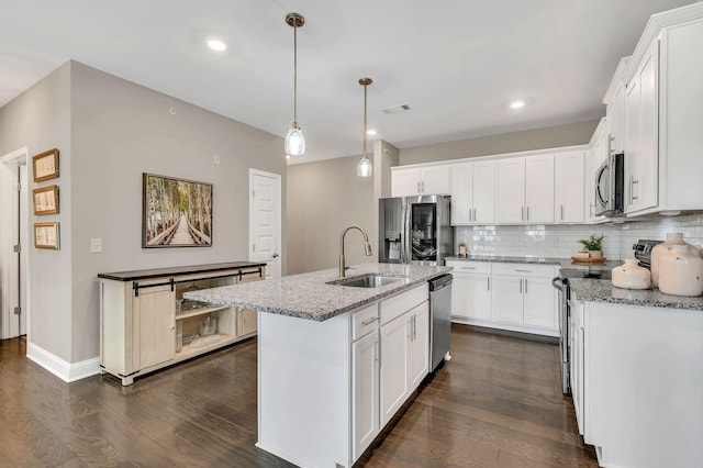 kitchen featuring an island with sink, stainless steel appliances, white cabinetry, and sink