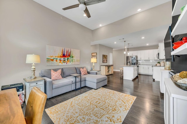 living room with dark hardwood / wood-style floors, ceiling fan, and a towering ceiling