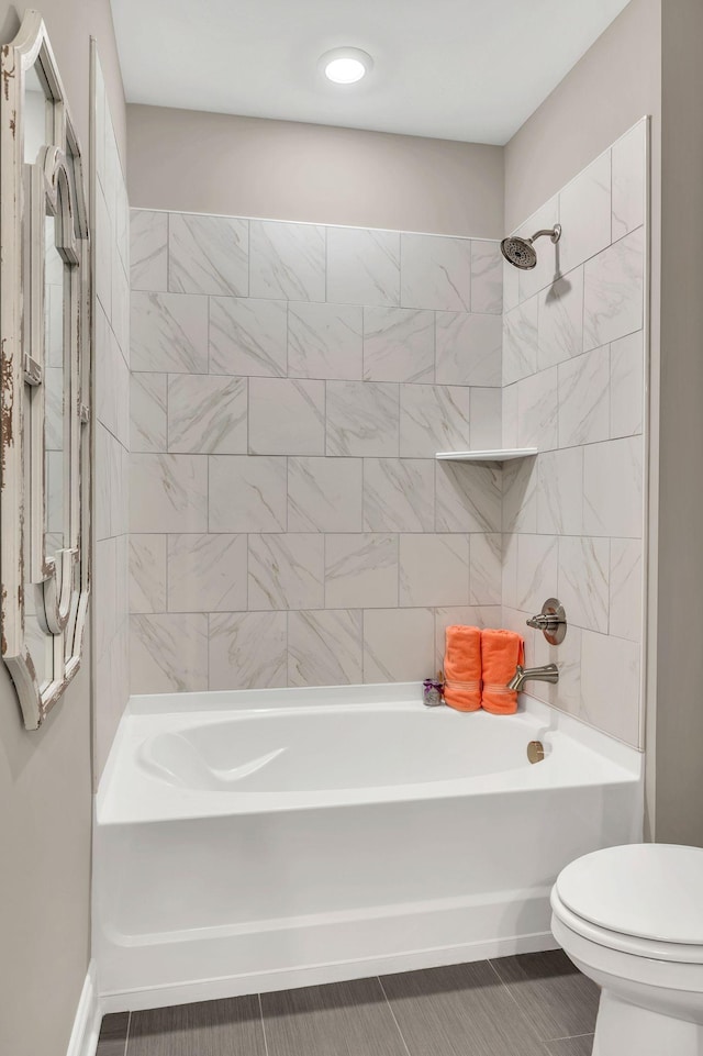 bathroom featuring tile patterned floors, tiled shower / bath combo, and toilet