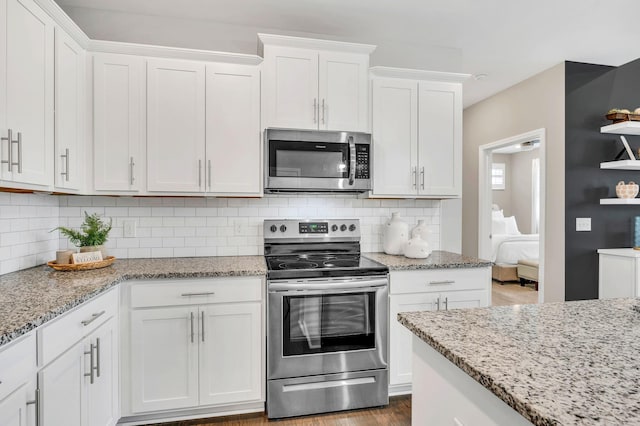 kitchen featuring decorative backsplash, white cabinetry, hardwood / wood-style floors, and stainless steel appliances