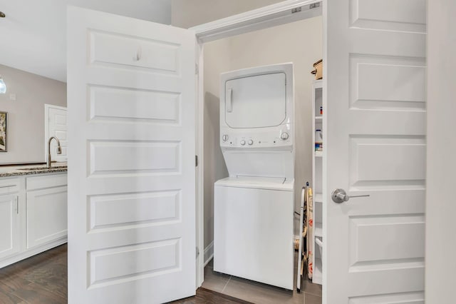 washroom featuring stacked washer and dryer, dark hardwood / wood-style flooring, and sink